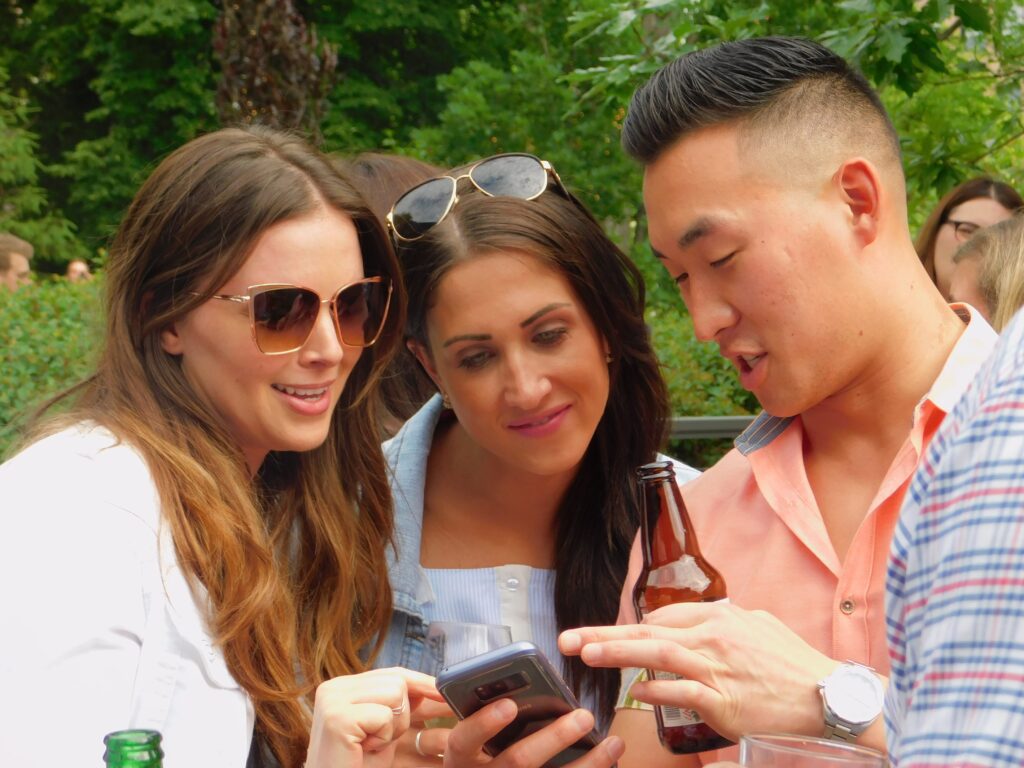 3 adults looking at phone